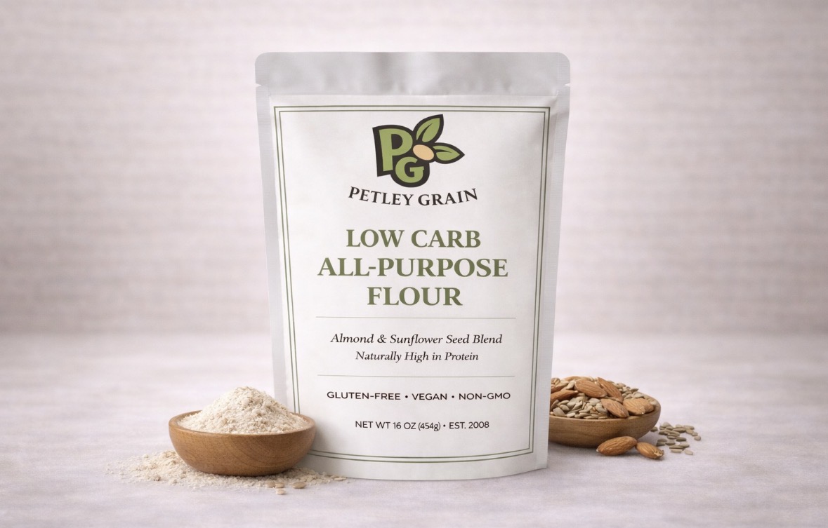 Petley Grain Low-Carb All-Purpose Flour pouch on a linen background with almonds, sunflower seeds, and a wooden bowl of flour